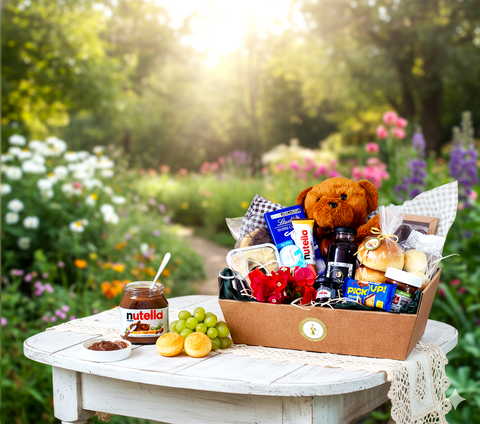 Cesta de café da manhã infantil com ursinho, Nutella, biscoitos e frutas em mesa no jardim florido.