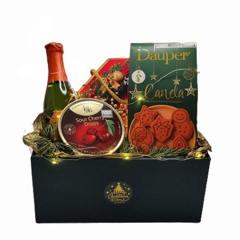 Cesta de Natal Encanto Natalino da Maria Madame montada em uma caixa rígida verde elegante. O kit presente contém um Espumante Aurora Baby Prosecco, lata de balas importadas Cavendish & Harvey sabor frutas silvestres, caixa de biscoitos de canela Dauper e chocolates finos Bolci.